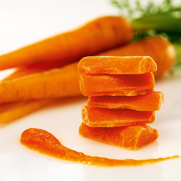 Fryst morotspuré med färska morötter i bakgrunden