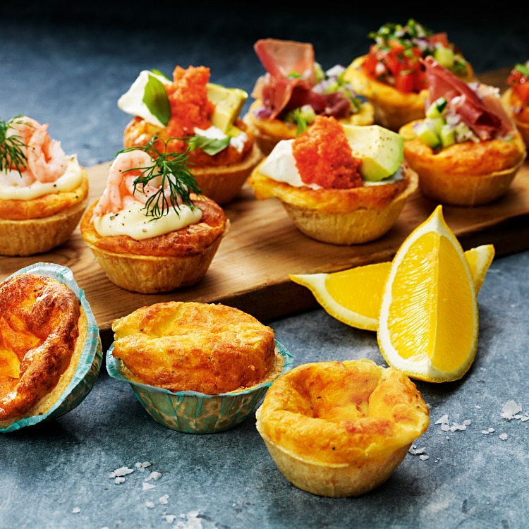Små ostpajer med olika toppings som räkor avokado och rom